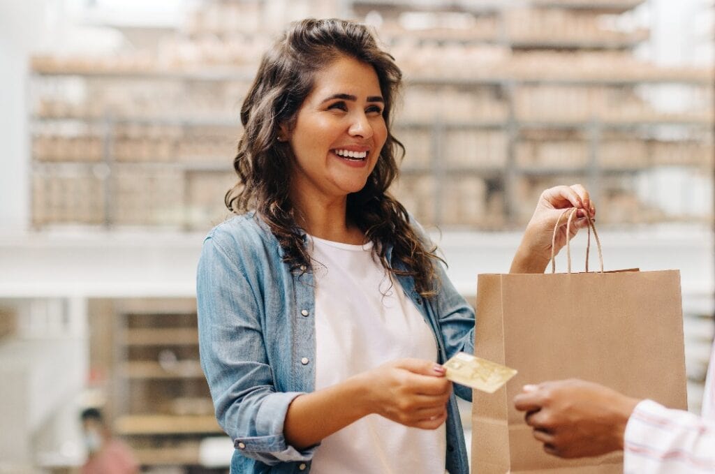 Happy female customer paying with a credit card in a ceramic store